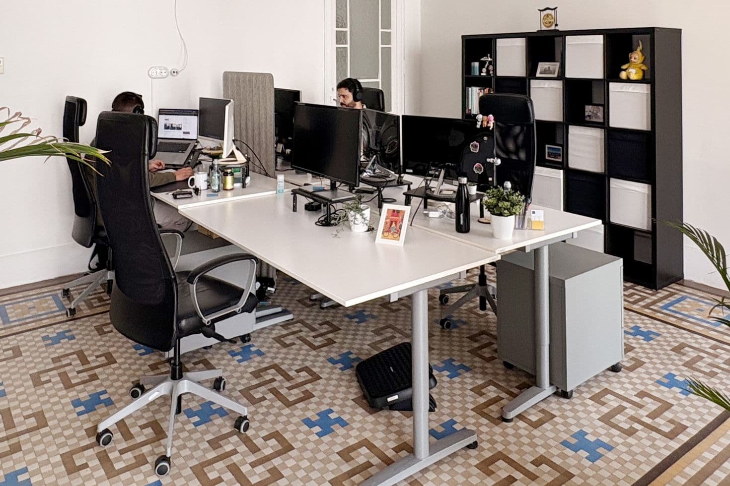 Innenansicht des Büros der nexum im spanischen Valencia mit Mosaikfußboden, Schreibtischen und Regalen.
