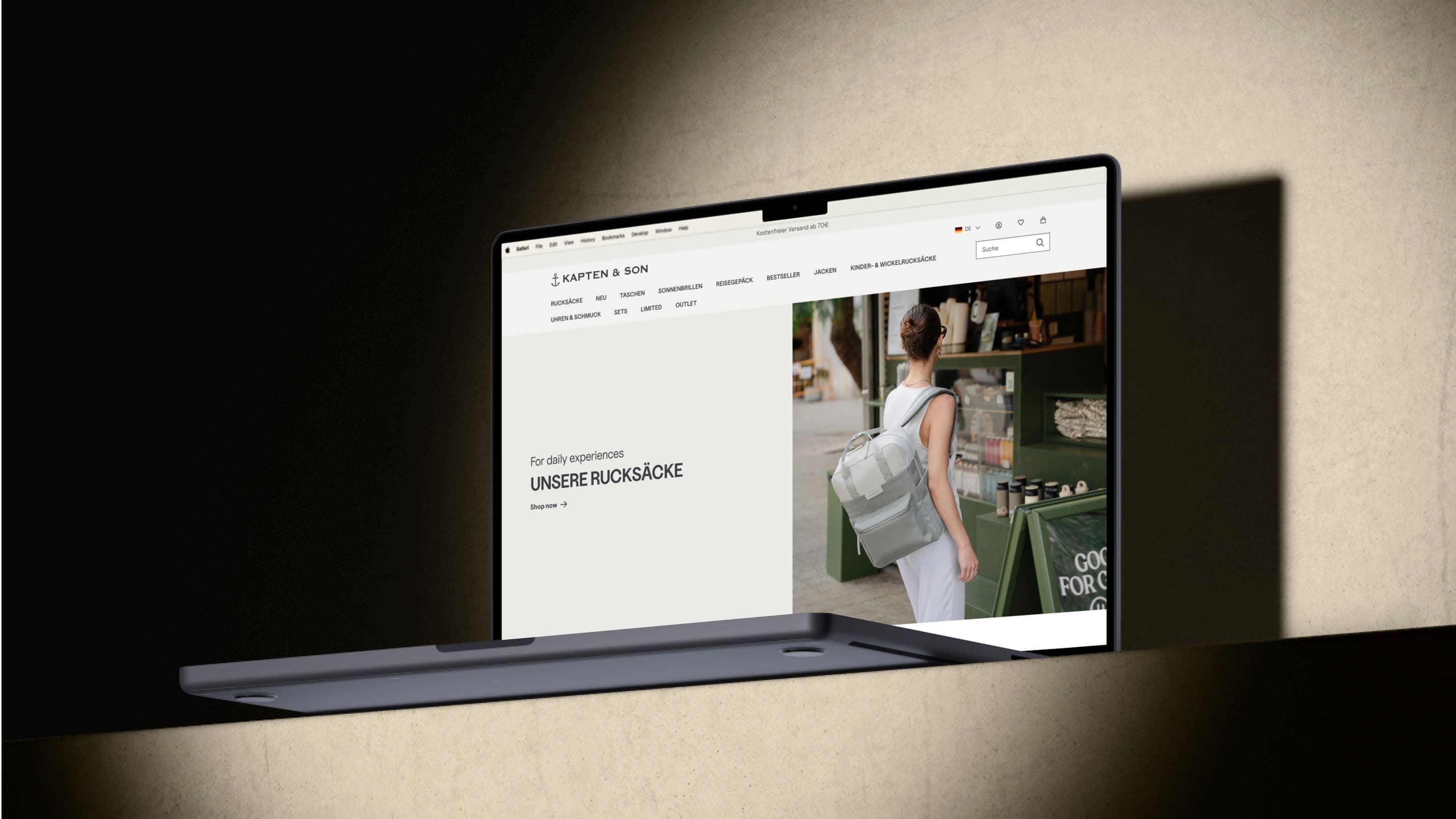 Ein aufgeklapptes Notebook zeigt die Kategorieseite "Rucksäcke" vom Kapten & Son Shop